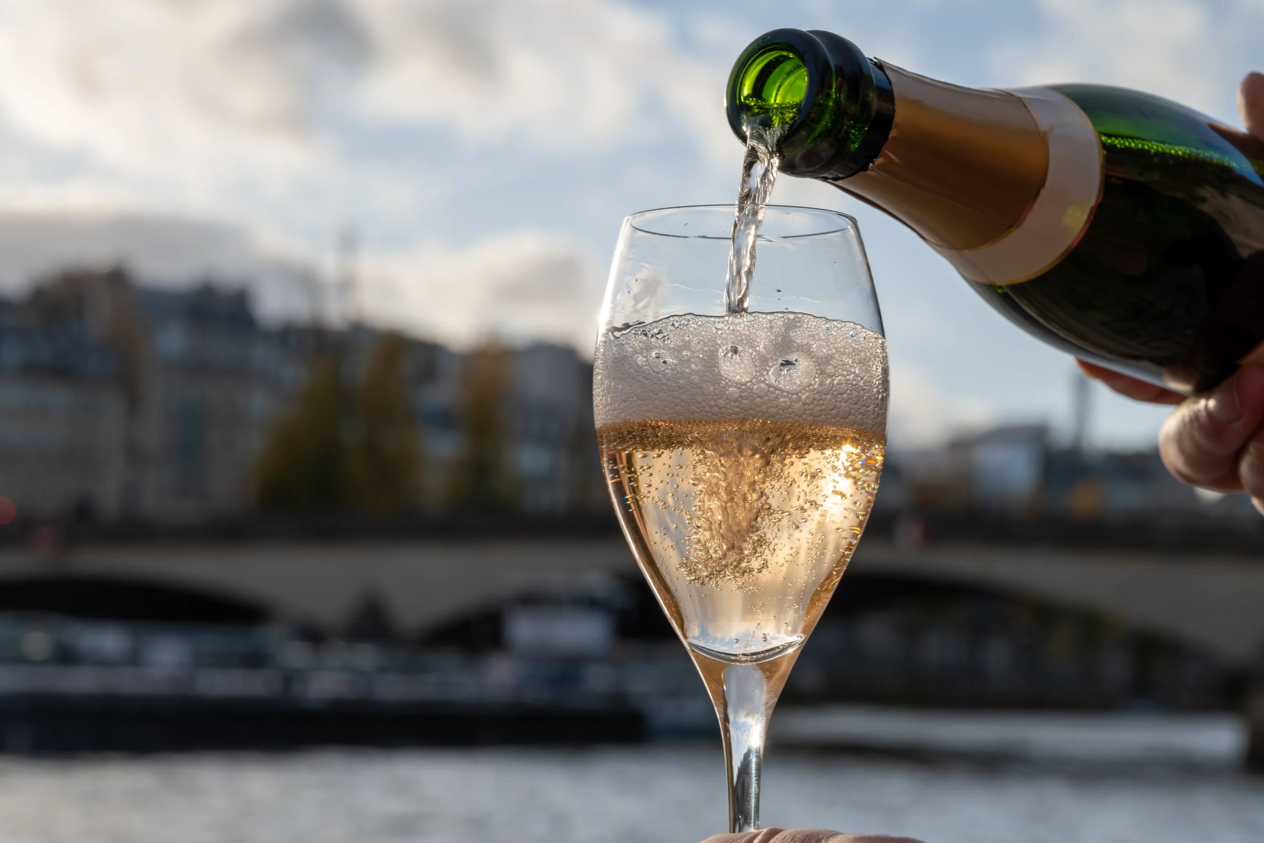 Pouring and drinking of french sparkling wine champagne during guided Seine cruise